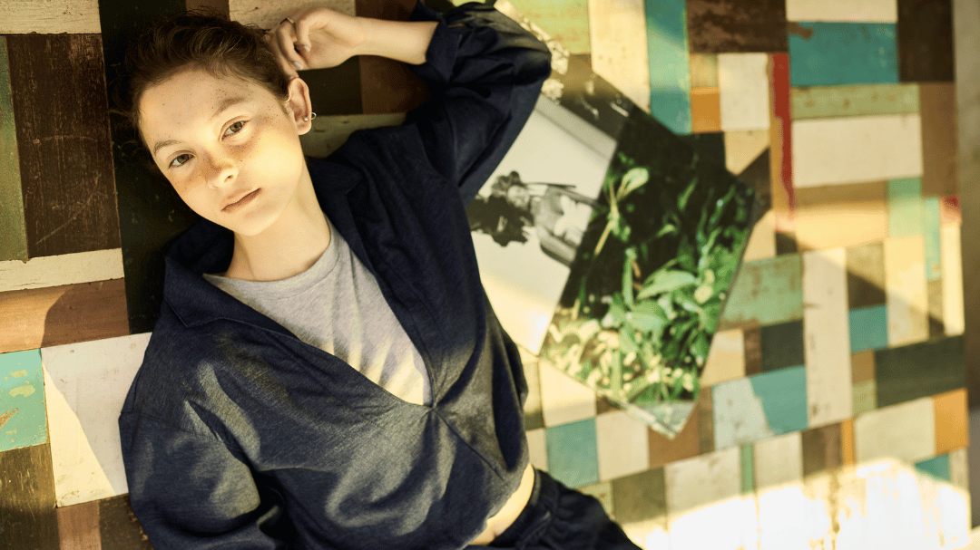 ICÔNE 秋冬形象滑動圖，左側為金色格紋牆面，中間模特在玻璃磚背景下穿著藍色襯衫與點點領帶，頭頂有舞台燈投射光線，右側為黑白現代建築外觀，呈現都市時尚與藝術感的對比視覺。