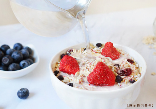 水倒入整碗厚奶水果燕麥-莓果，內容物包含冷凍乾燥草莓、藍莓，與蔓越莓果乾。加水沖泡即可享用。
