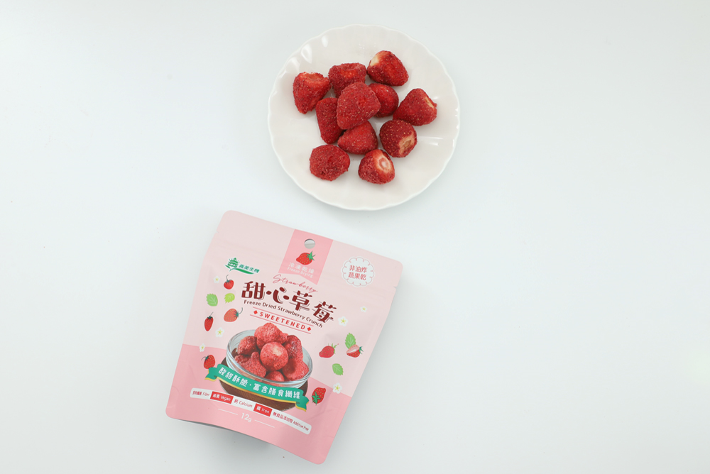義美生機甜心草莓的包裝袋及果乾內容物，冷凍乾燥整顆草莓擺放在白色圓盤上。