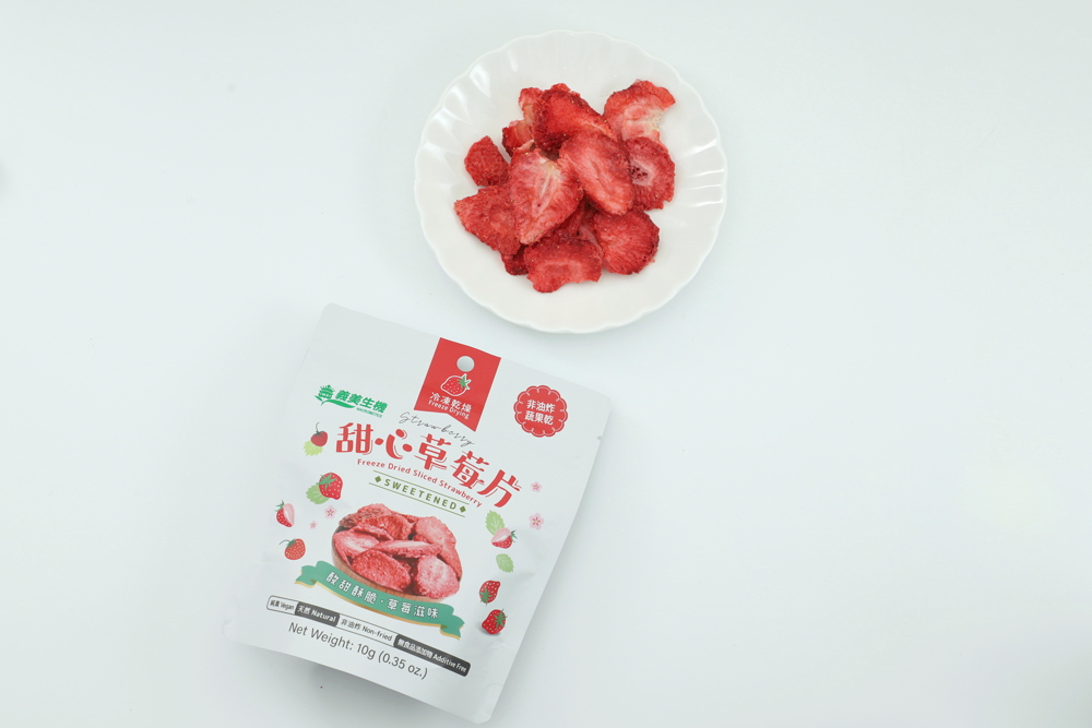 義美生機甜心草莓片的包裝袋及果乾內容物，冷凍乾燥草莓片擺放在白色圓盤上。