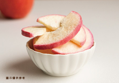 一碗白色瓷碗裝著的凍乾蘋果片的特寫照。