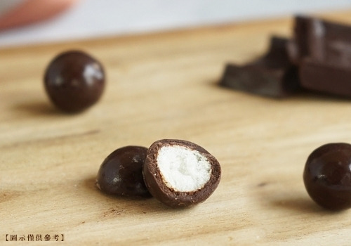 木頭砧板上放了幾顆黑巧米果，有一顆被咬了一半，可看見白色的米果被巧克力包裹住。