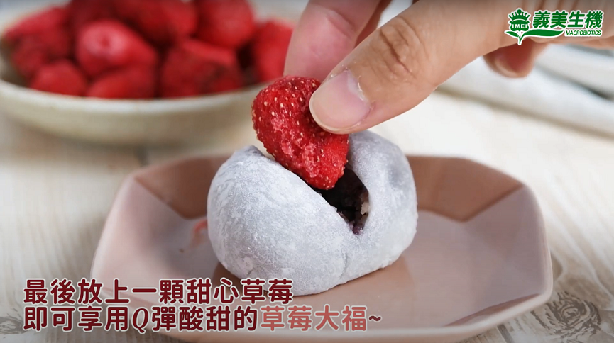 製作草莓大福的最後步驟，在紅豆大福上切一個開口並放上一整顆凍乾草莓。